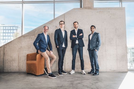 Four men standing in front of a concrete wall.