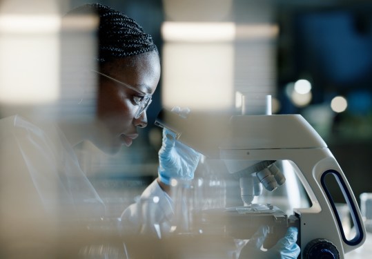 Scientist, microscope and analysis in lab for healthcare and drug discovery