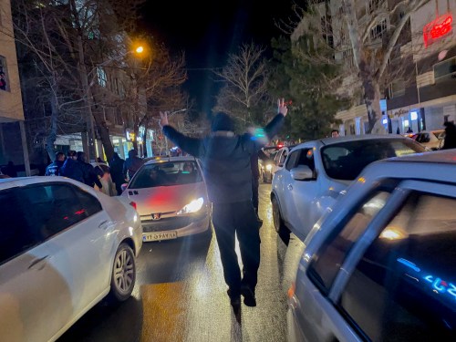 A protester flashes victory signs as traffic slows during demonstrations in Hamedan, Iran, on January 1, 2026.