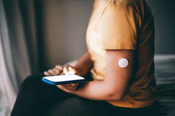 person sitting, with glucose monitor on their arm